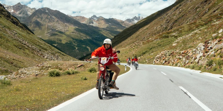 Mofa-Ausfahrt durch die Alpen Gruppe fährt mit Mofas eine kurvige Alpenstraße entlang
